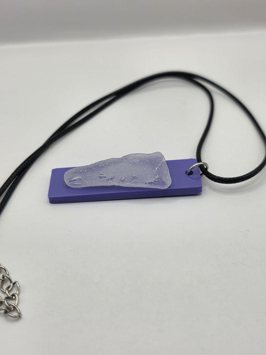 Sea glass pendant necklace on a purple background with black waxed cord adjustable necklace