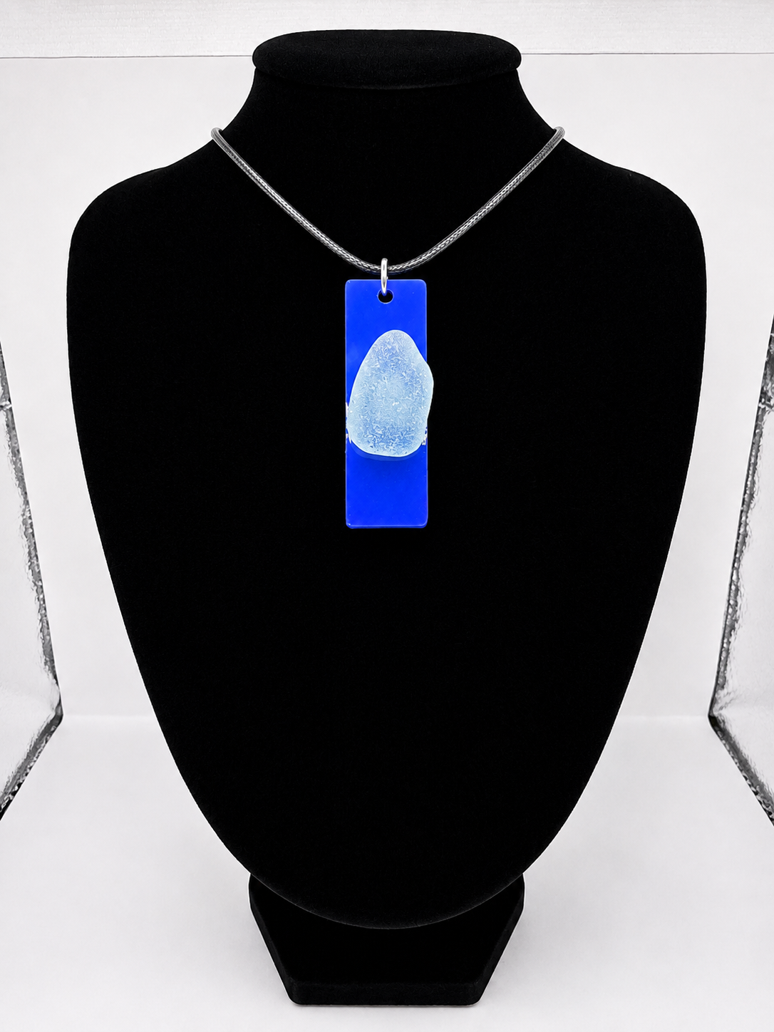 Sea glass pendant necklace on a blue background with black waxed cord adjustable necklace