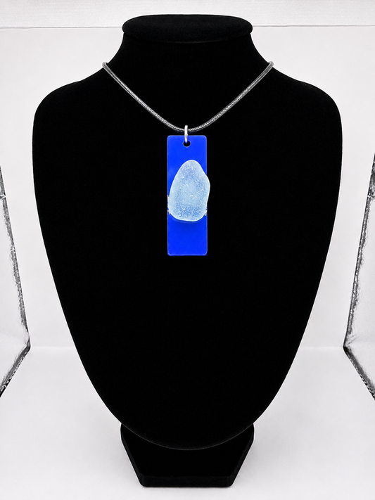 Sea glass pendant necklace on a blue background with black waxed cord adjustable necklace