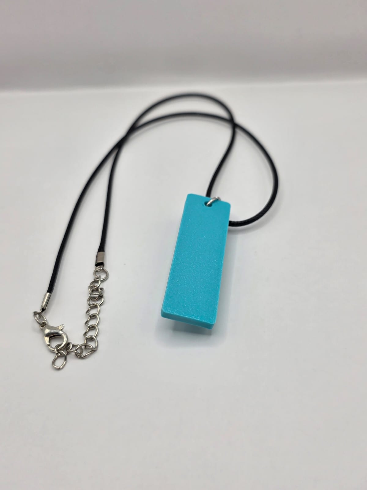 Sea glass pendant necklace on a light blue background with black waxed cord adjustable necklace