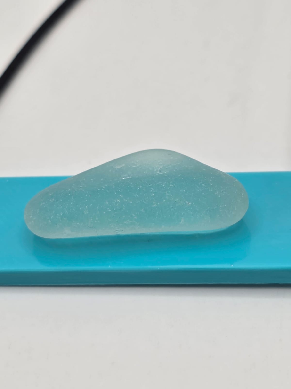 Sea glass pendant necklace on a light blue background with black waxed cord adjustable necklace