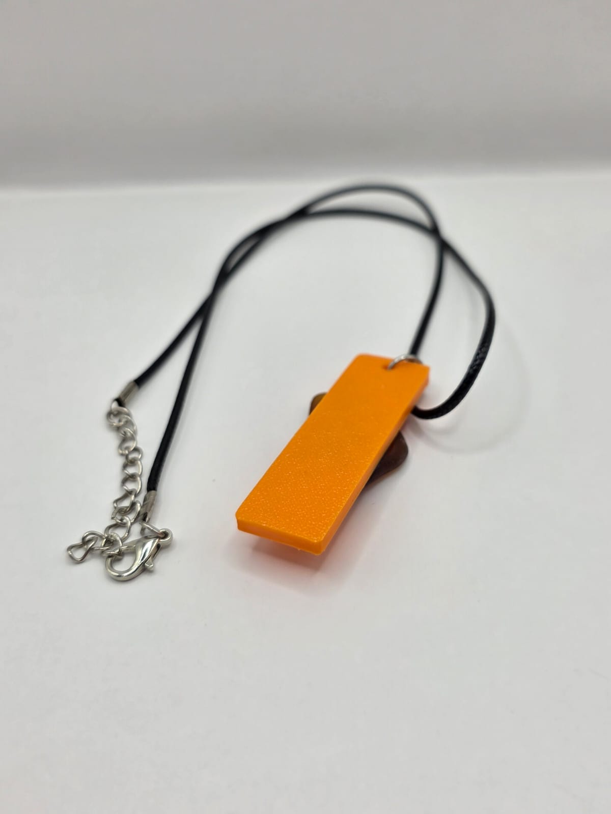 Sea glass pendant necklace on a orange background with black waxed cord adjustable necklace