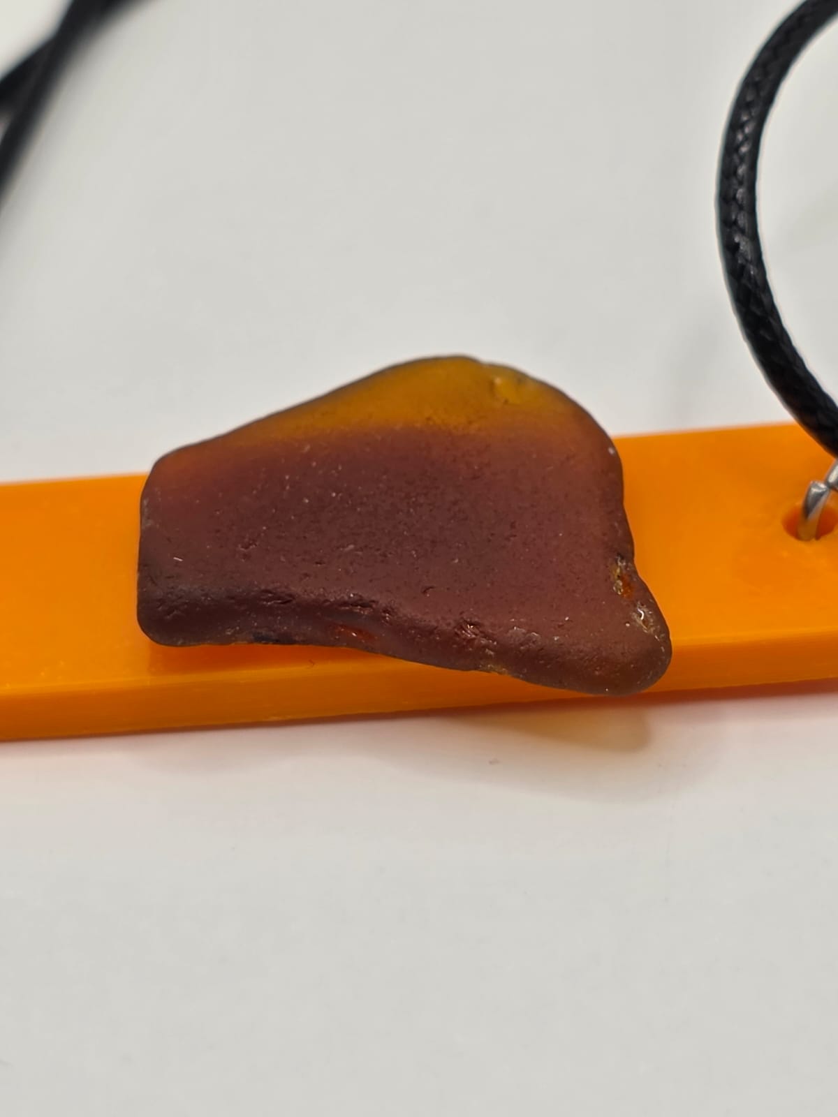 Sea glass pendant necklace on a orange background with black waxed cord adjustable necklace