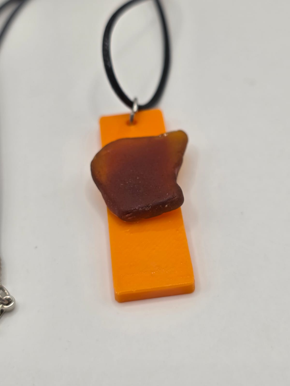 Sea glass pendant necklace on a orange background with black waxed cord adjustable necklace