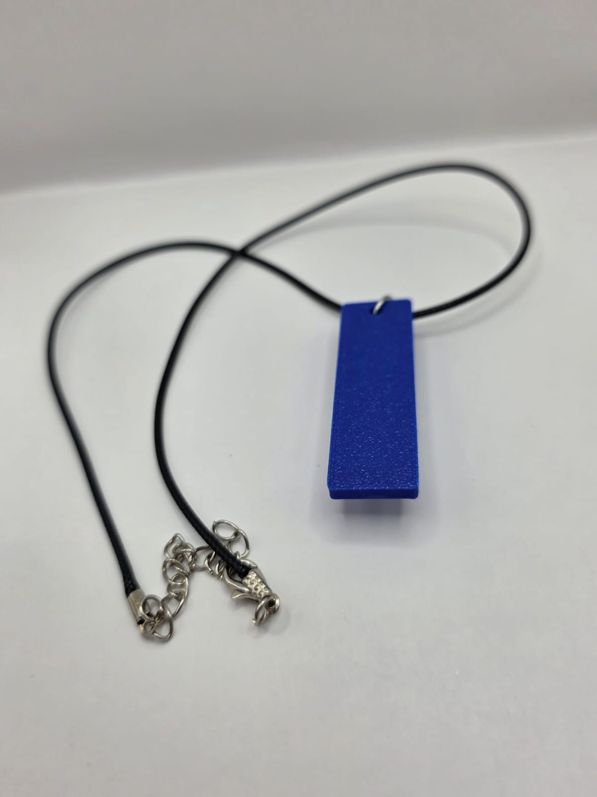 Sea glass pendant necklace on a blue background with black waxed cord adjustable necklace