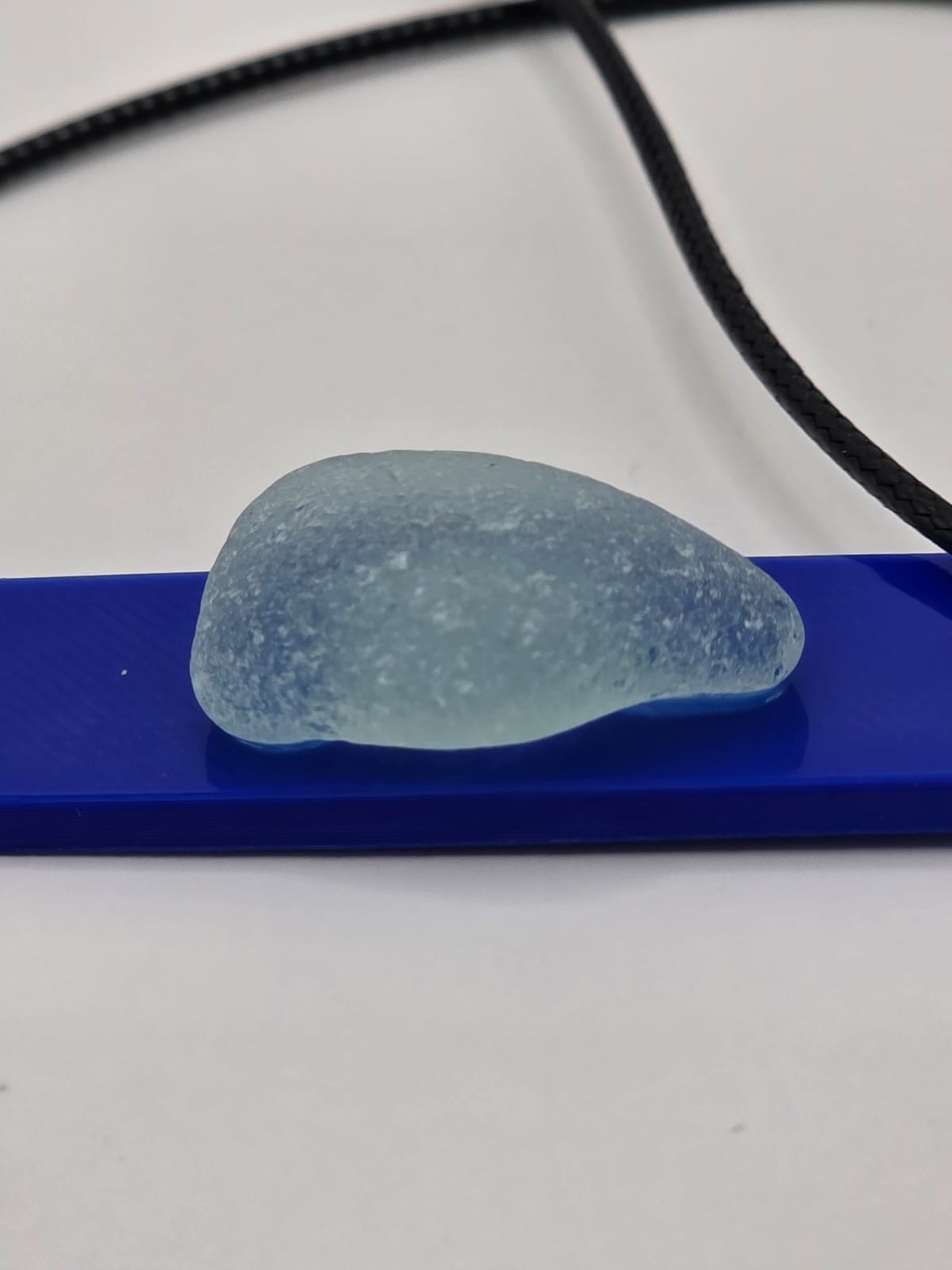 Sea glass pendant necklace on a blue background with black waxed cord adjustable necklace
