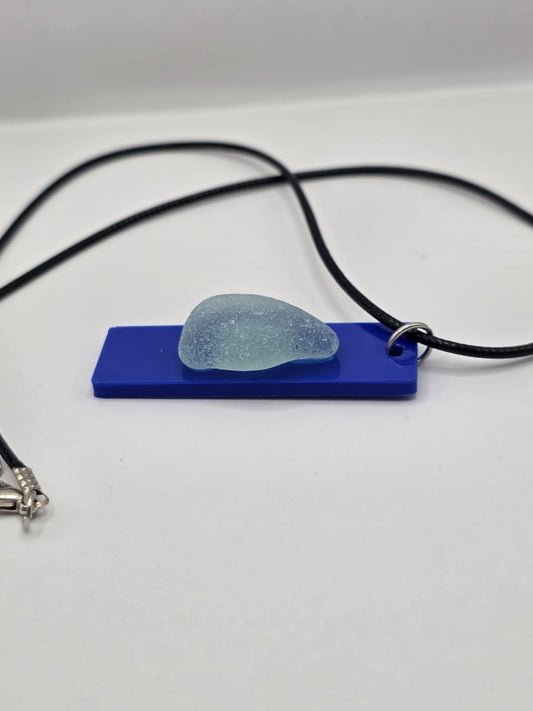 Sea glass pendant necklace on a blue background with black waxed cord adjustable necklace