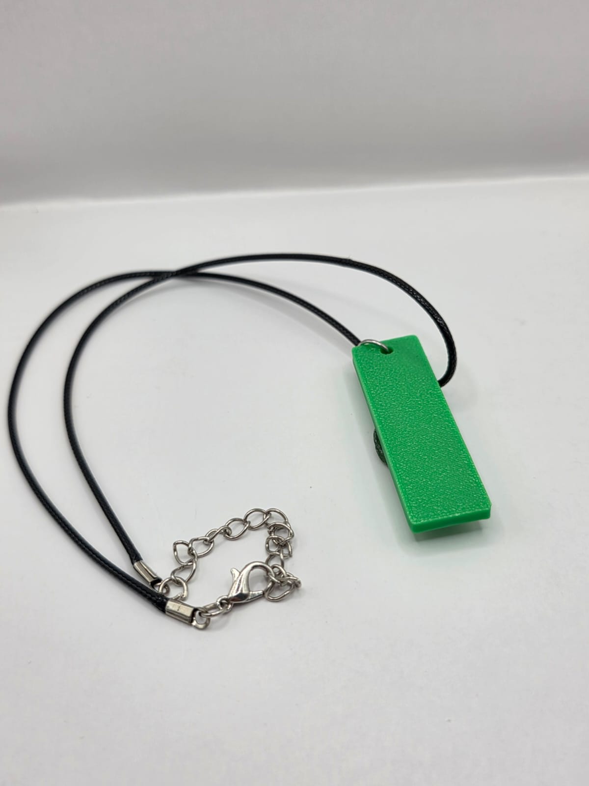 Sea glass pendant necklace on a green background with black waxed cord adjustable necklace