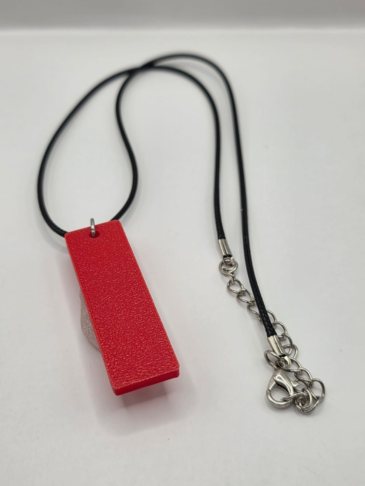 Sea glass pendant necklace on a red background with black waxed cord adjustable necklace