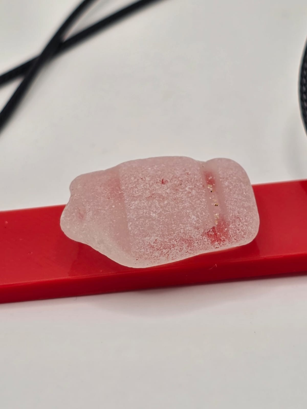 Sea glass pendant necklace on a red background with black waxed cord adjustable necklace