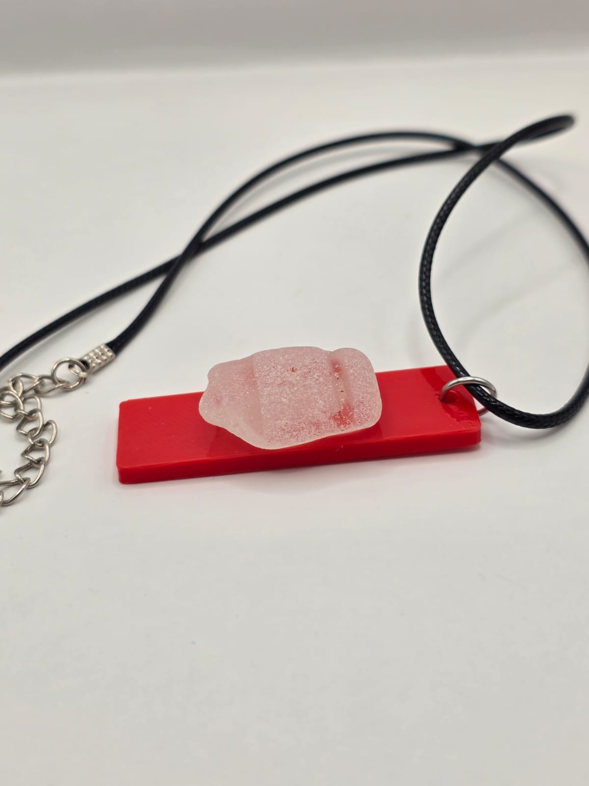 Sea glass pendant necklace on a red background with black waxed cord adjustable necklace