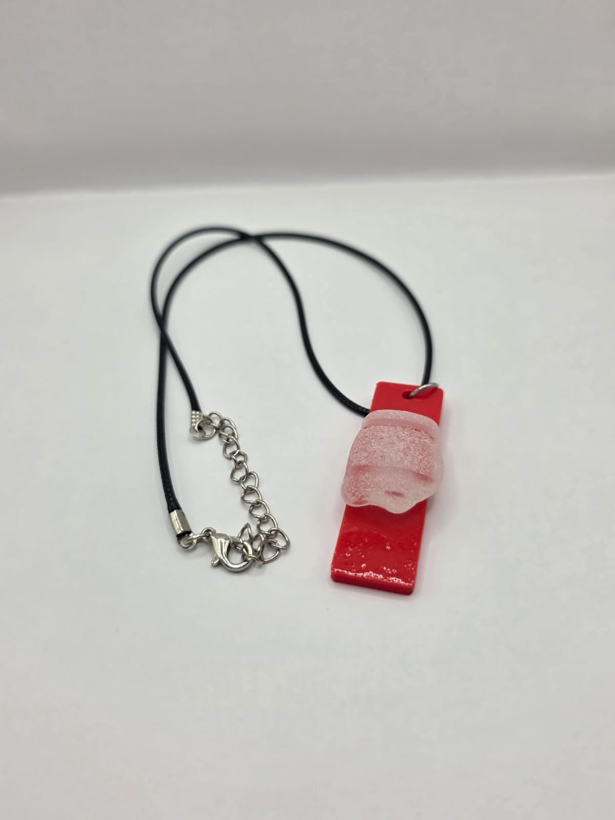 Sea glass pendant necklace on a red background with black waxed cord adjustable necklace