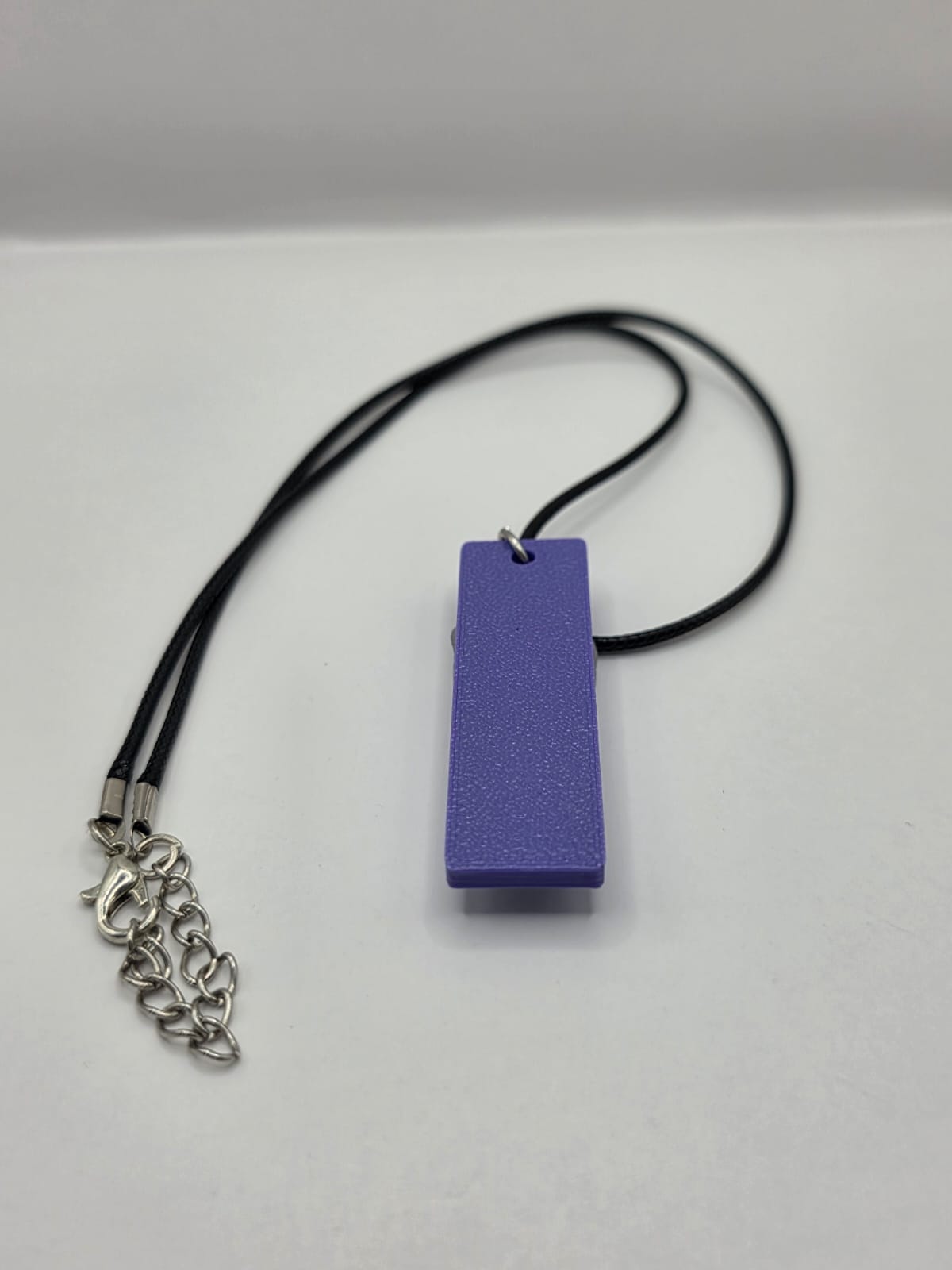 Sea glass pendant necklace on a purple background with black waxed cord adjustable necklace