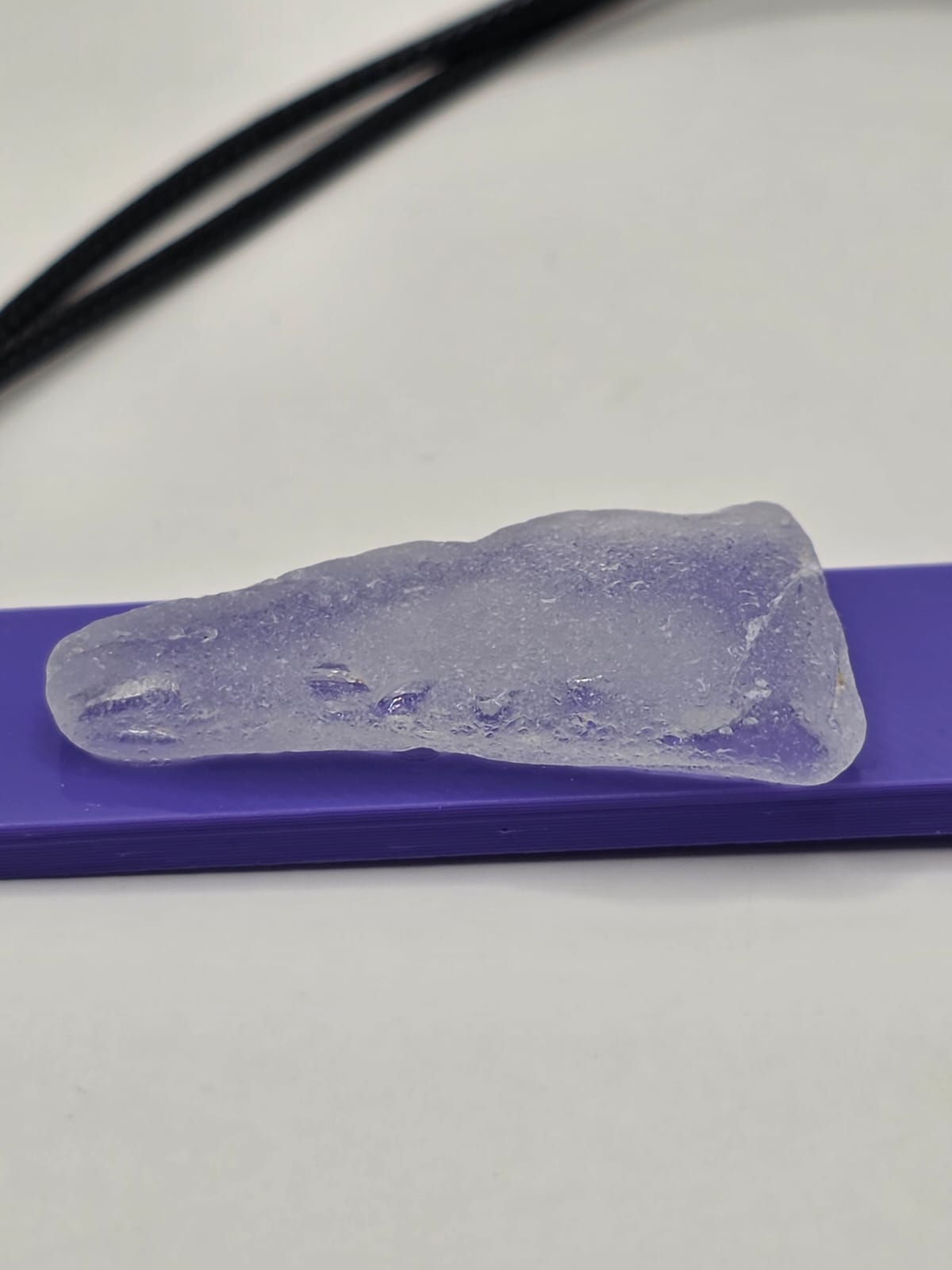 Sea glass pendant necklace on a purple background with black waxed cord adjustable necklace