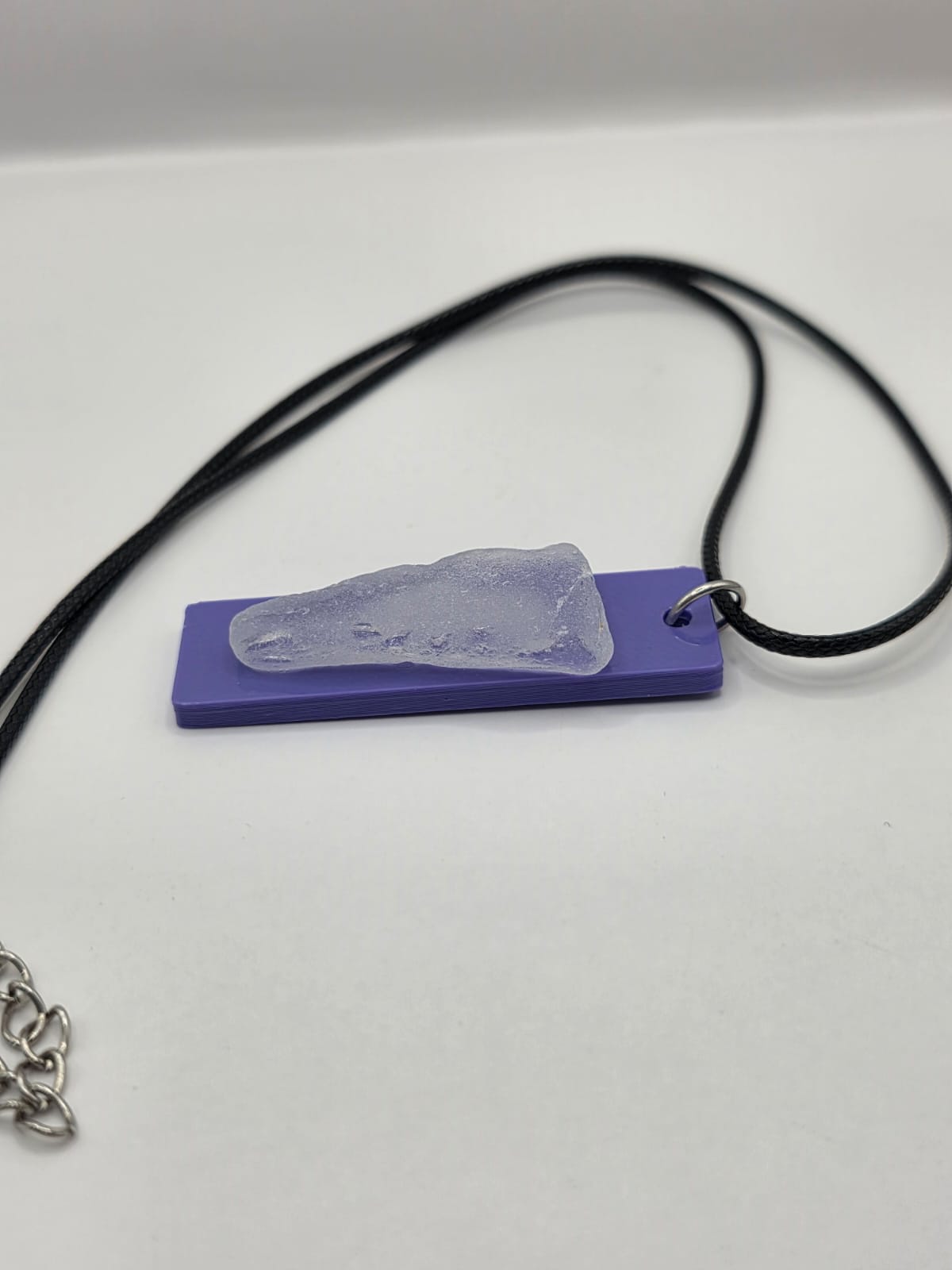 Sea glass pendant necklace on a purple background with black waxed cord adjustable necklace