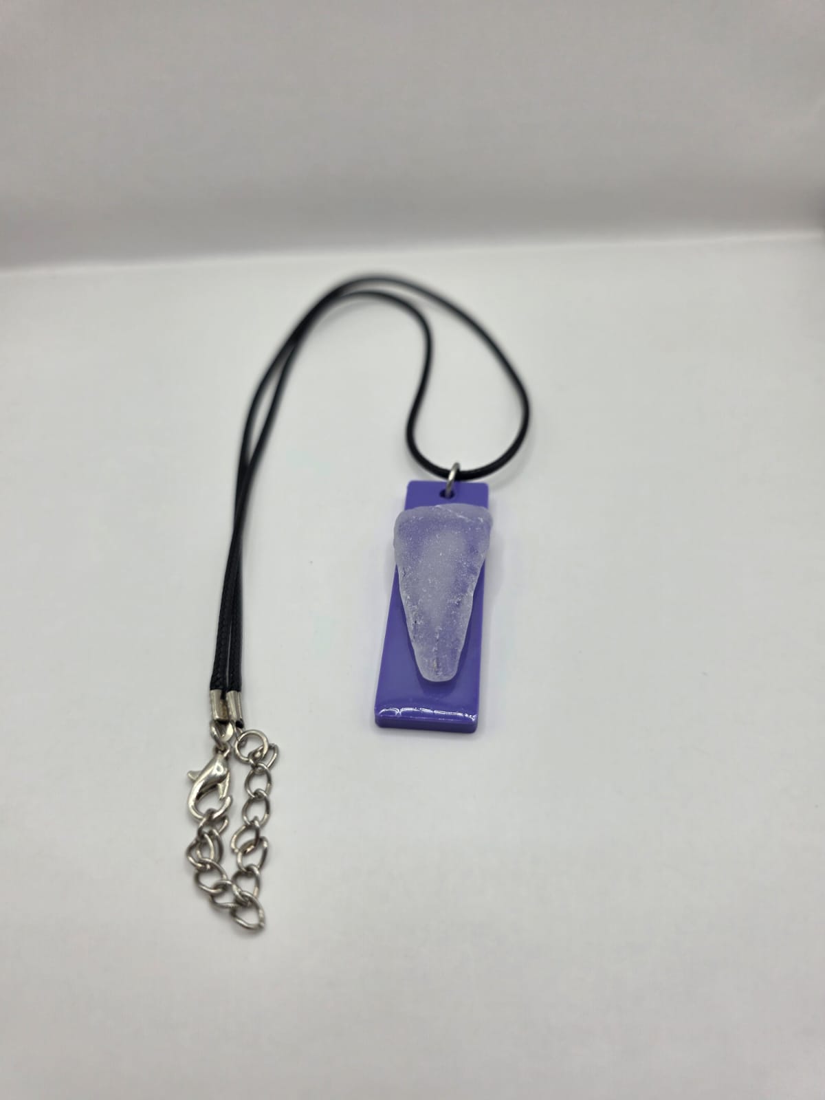 Sea glass pendant necklace on a purple background with black waxed cord adjustable necklace
