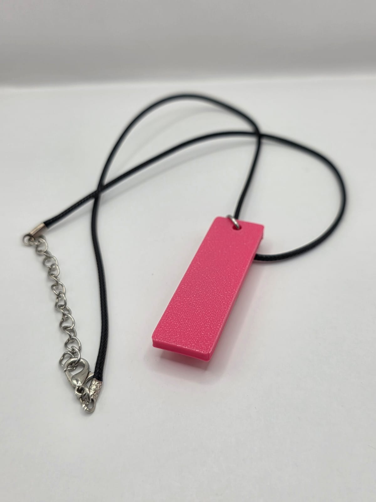 Sea glass pendant necklace on a pink background with black waxed cord adjustable necklace
