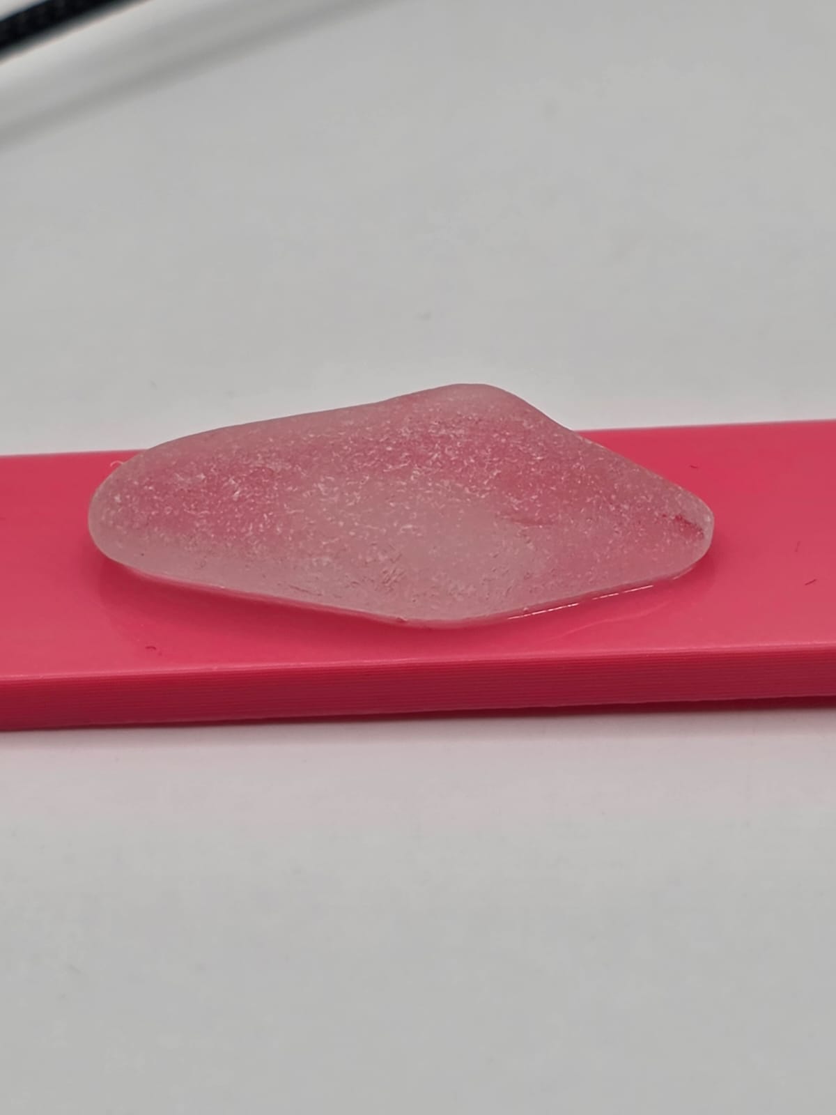 Sea glass pendant necklace on a pink background with black waxed cord adjustable necklace