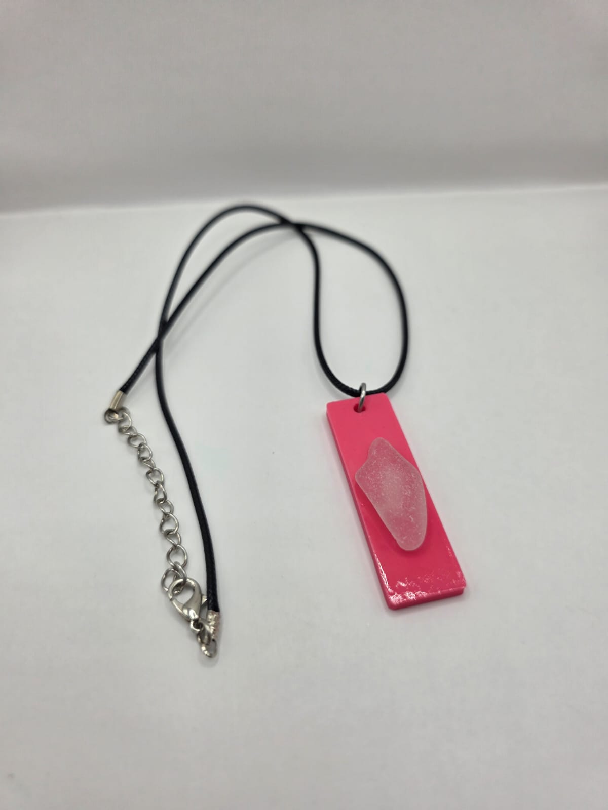Sea glass pendant necklace on a pink background with black waxed cord adjustable necklace