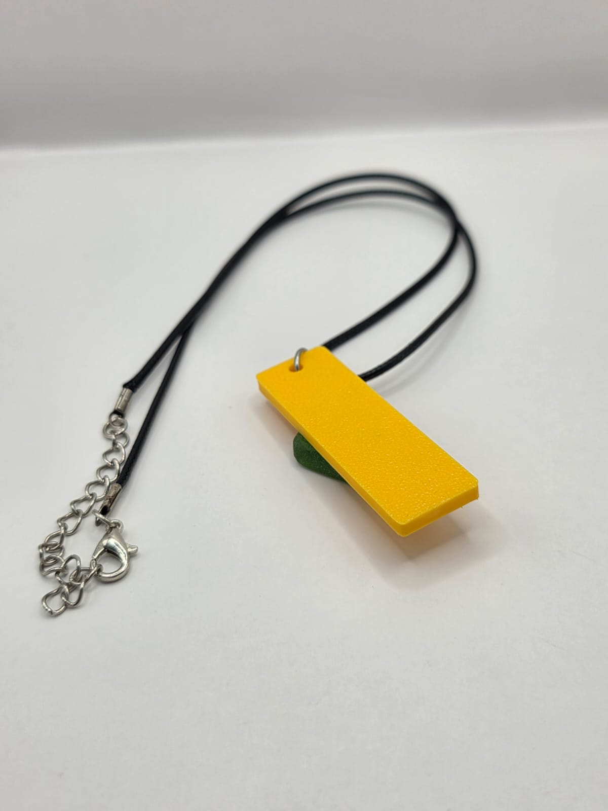 Sea glass pendant necklace on a yellow background with black waxed cord adjustable necklace