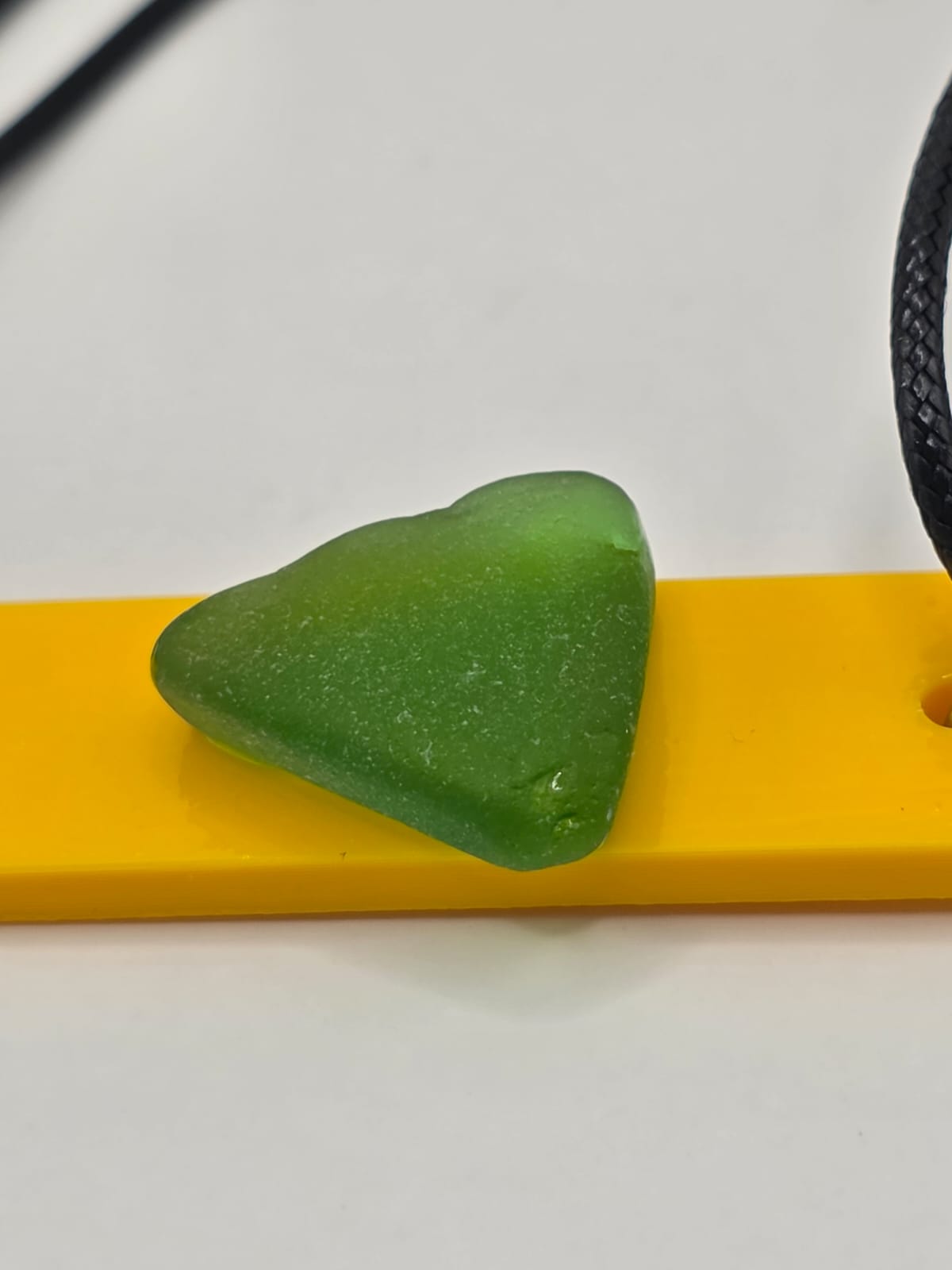Sea glass pendant necklace on a yellow background with black waxed cord adjustable necklace