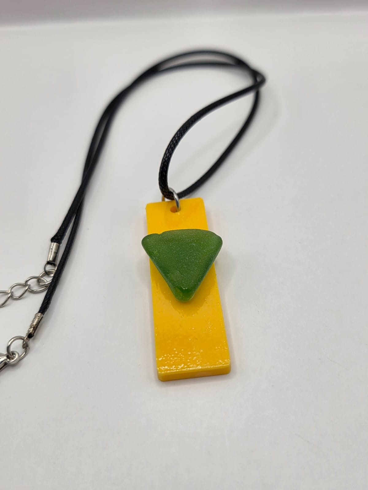 Sea glass pendant necklace on a yellow background with black waxed cord adjustable necklace