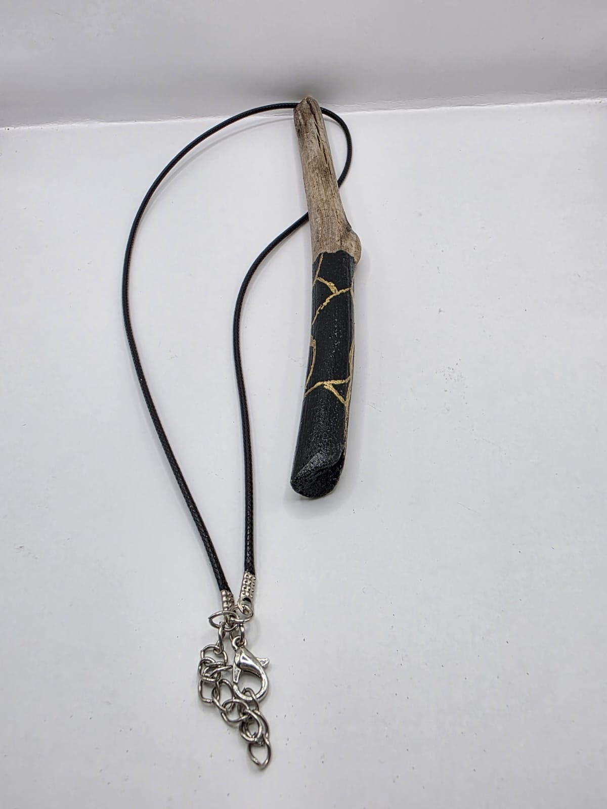 Long driftwood pendant necklace featuring black and gold kintsugi style design