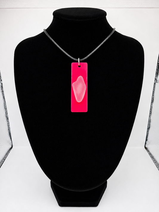 Sea glass pendant necklace on a pink background with black waxed cord adjustable necklace