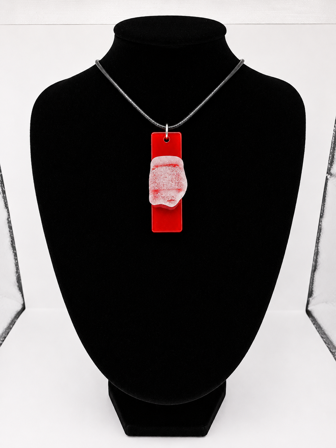 Sea glass pendant necklace on a red background with black waxed cord adjustable necklace